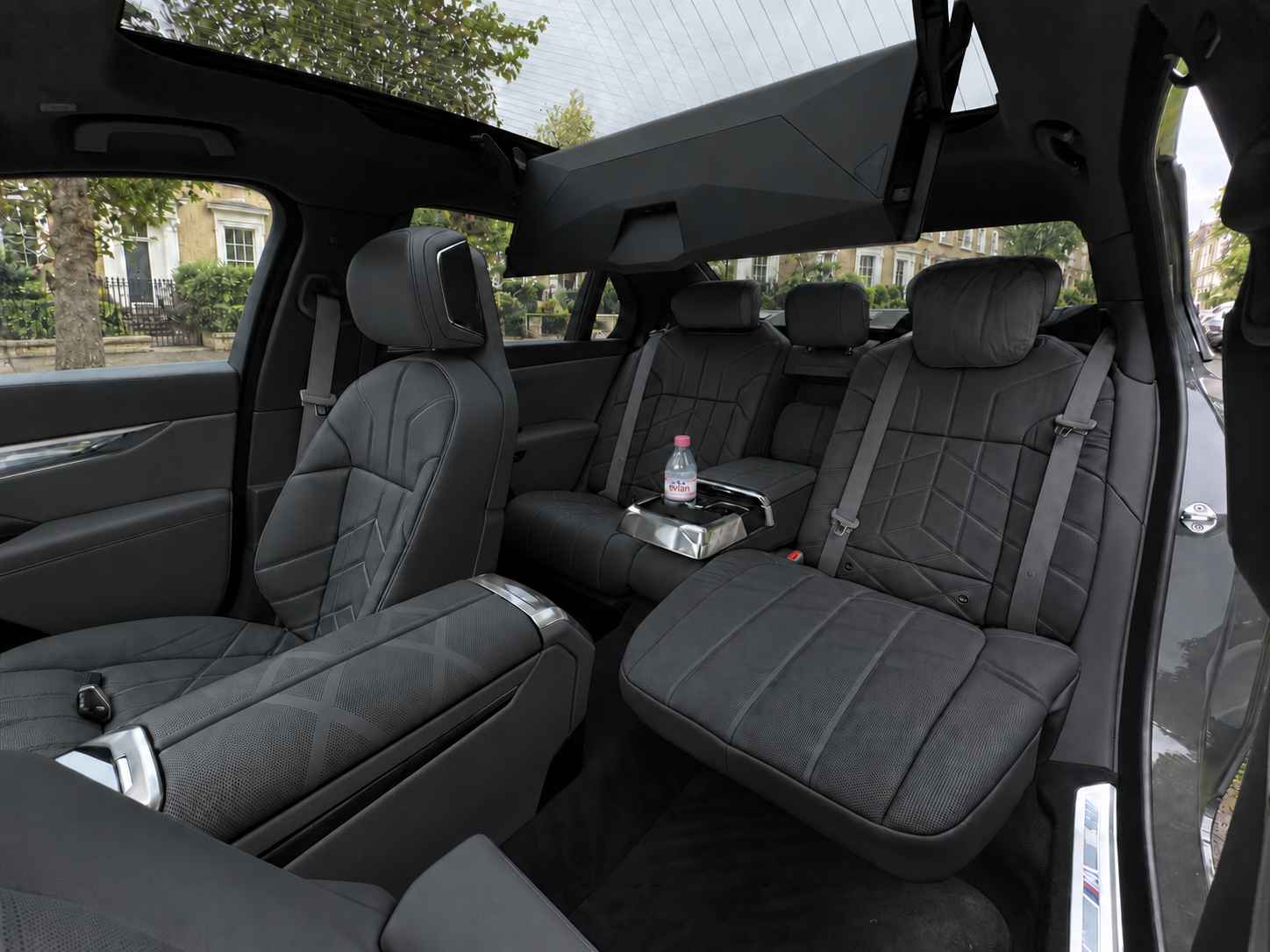 BMW i7 interior with black leather seats, bottled water and a London street outside